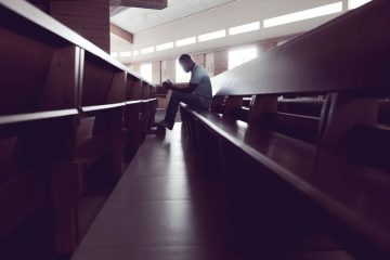 homem ajoelhado no banco da igreja orando
